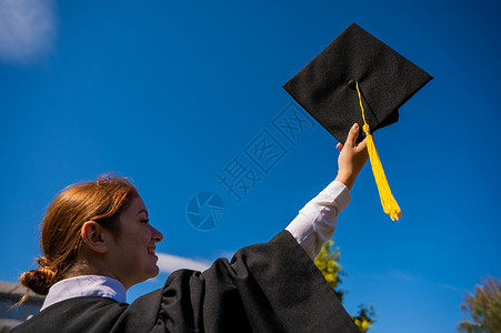 一个女人把她的毕业帽扔在蓝天上快乐天空幸福文凭女性蓝色仪式空气帽子学生祝贺高清图片素材
