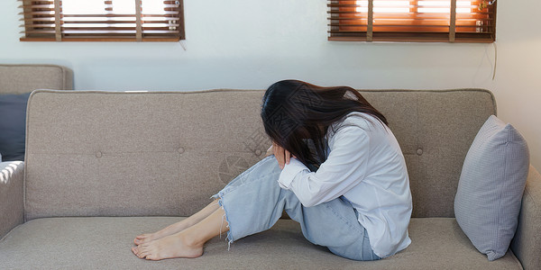 年青的亚洲妇女在家里沙发上感到悲惨和孤单女性就寝苏醒焦虑电话卧室手机失眠孤独枕头沮丧高清图片素材