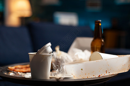 食物罐和啤酒瓶放在脏乱的桌子上的空剩菜图片素材