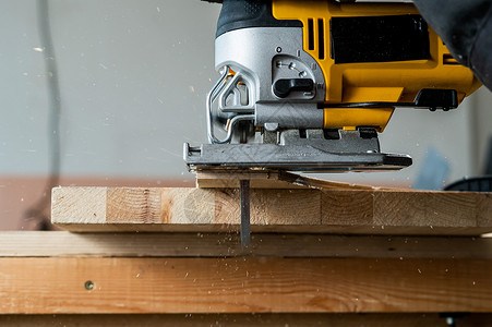 一名男子在车间用电锯砍木板的缝合装置上木工家具机器乐器桌子作坊工作材料木制品工作台木材高清图片素材
