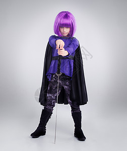 七剑下天山小女孩 超级英雄和万圣节装扮在灰色工作室背景下用剑摆姿势 扮演超级英雄的女童肖像 紫色头发 服装或武士义警的角色扮演背景