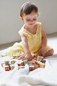 她是个聪明的小女孩 一个坐在地板上玩玩具小块儿的可爱女婴生长高清图片素材
