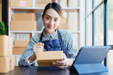 独立亚洲女性在线卖家包装产品的小型企业企业家发送给客户和中小企业交付概念女孩店铺销售量船运盒子成功商务网上购物电脑顾客背景图片