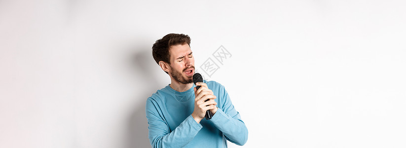 罗马男子在卡拉OK的麦克风里唱歌 站在白色背景上歌手广告成人生活卡拉ok办公室成功工作室促销情绪背景图片