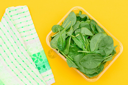 黄色背景透明塑料套件中新鲜的婴儿菠菜叶新片蔬菜树叶绿叶食物排毒绿色饮食减肥草本植物植物背景图片