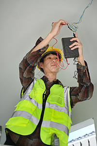 电工的图像 他手里拿着一个工具 在建筑工地用电缆工作建造高清图片素材