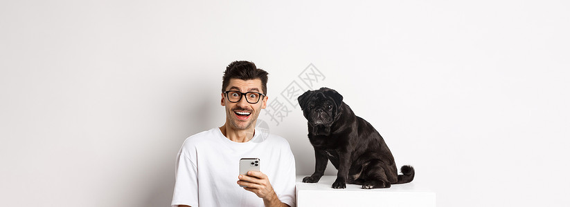 带着可爱的黑小狗坐着 使用手机 站在白色背景上 Y I L K 我胡须犬类乐趣电话动物行动横幅宠物促销快乐背景图片
