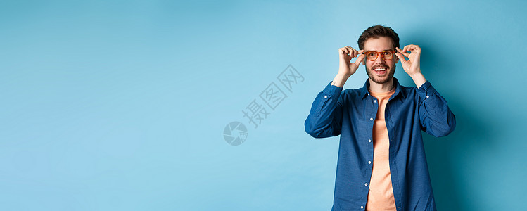 欢乐的caucaosian男人尝试新的眼镜和微笑 站在蓝背景上胡须广告胡子发型促销情绪工作室店铺生活成功背景图片