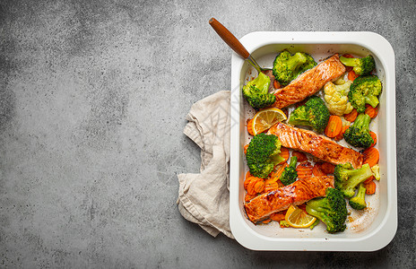 在灰石背景的砂锅菜中 可以看到健康的烤鱼鲑鱼排 西兰花 花椰菜 胡萝卜 烹饪美味的低碳水化合物晚餐 健康的营养理念 文字空间午餐背景图片