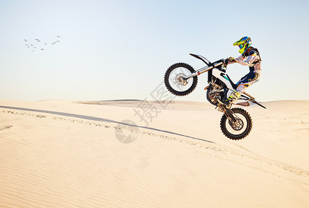 远动服适合具有敏捷速度 力量或自然平衡能力的极限运动专家的摩托车 沙漠赛跑和空中跳跃 骑摩托车的人 集会和蓝天 骑着带头盔 安全服或动背景