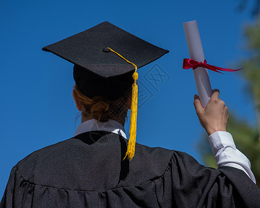 背着蓝天的毕业礼服 拥有文凭的caucasian女人的视线欣喜若狂高清图片素材