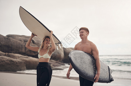 和爱人一起做我爱做的事 在海滩边的一对年轻夫妇 带着冲浪板背景图片