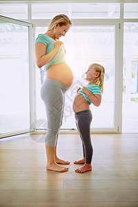 也要常回家看看你也想看看我的肚子吗? 一个孕妇和她的女儿 在家里互相露出胃来看对方的肚子吧背景