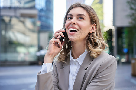 快乐的女商务人士在手机上聊天 笑笑和微笑 站在城外户外的肖像发短信高清图片素材