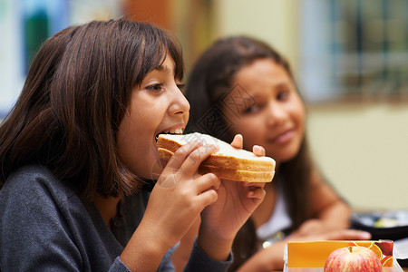 休息时享用三明治 午餐时间 一名年轻的女学生在自助餐厅吃三明治学习高清图片素材