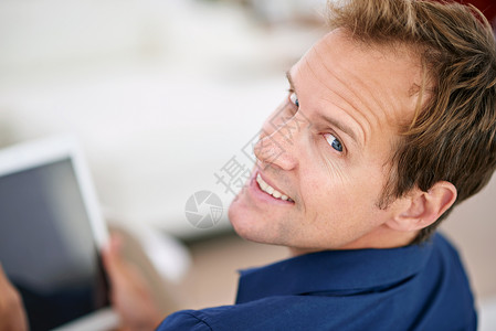 保持联络从来就不是那么容易的事 一个英俊的男人在家里用平板电脑的肖像背景图片