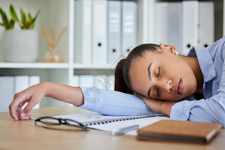 累了 睡着了 坐在桌子上做生意的女人在办公室里睡觉时感到精疲力竭和过度劳累 午睡 做梦和疲惫不堪 疲惫的女商务人士在工作时在桌子工人高清图片素材