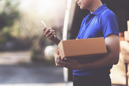 具有包裹和配送物流概念的亚洲快递员 通过智能手机使用送货应用程序的送货员邮政船运货车男人施工商业卡车邮递员贮存盒子邮件高清图片素材