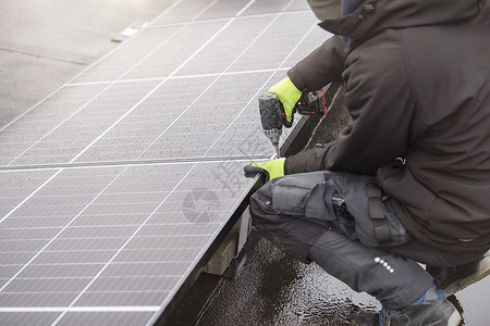 再生能源 绿色能源概念 安装太阳能电池板的过程 师傅拧紧太阳能电池板模块的安装工人蓝色建筑光伏房子细胞建造技术螺丝刀技术员背景图片