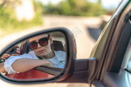 一辆新车里一位美丽的女人的肖像 在后视镜中看着一副后视镜青少年高清图片素材