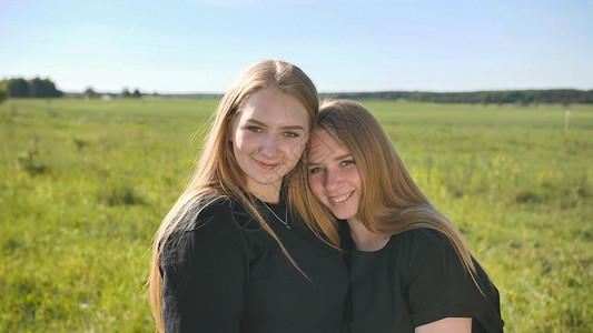 在温暖的夏日 两个姐妹在野外 被一个双姐妹画像亲戚们成人孩子头发姐妹女孩快乐女性闺蜜皮肤朋友们高清图片素材