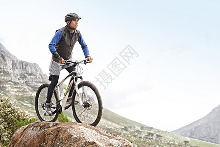 山自行车多么辉煌的足迹 一个年轻人骑着山地自行车 在崎岖的地形上背景