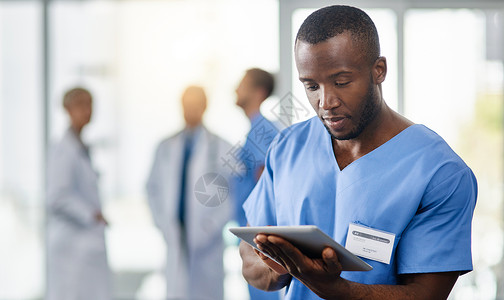 利用现代技术提高医疗诊断水平 一位年轻的医生和他的同事在后台使用数字平板电脑背景图片