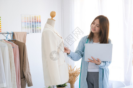 一位年轻的年轻女性时装设计师正在检查笔记本电脑上的客户在线订单网上商城高清图片素材