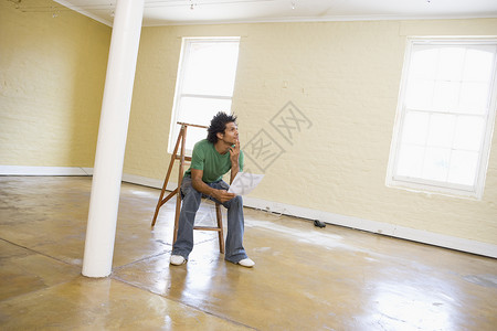 一个人坐在空空空间的梯子上 拿着纸思考高清图片