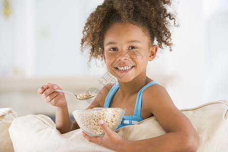 麦片碗里女孩年轻女孩在客厅里笑着吃麦片孩子儿童家庭早餐孩子们饮食食品食物一个女孩享受背景