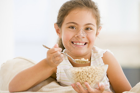 麦片碗里女孩年轻女孩在客厅里笑着吃麦片家庭健康饮食享受孩子们一个女孩水平孩子谷物儿童食品背景