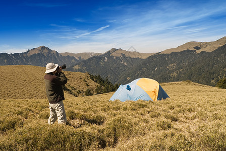 在高山草原上设置特别帐篷环境庇护所男人游客爬坡登山背包荒野阳光远足运动高清图片素材