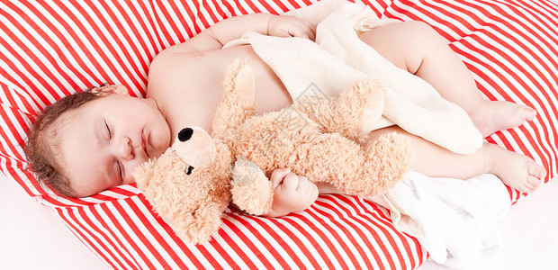 红色条纹枕头睡着的可爱小宝宝 在红色和白条纹枕头上孩子女儿毯子童年生活婴儿就寝家庭皮肤压痛背景