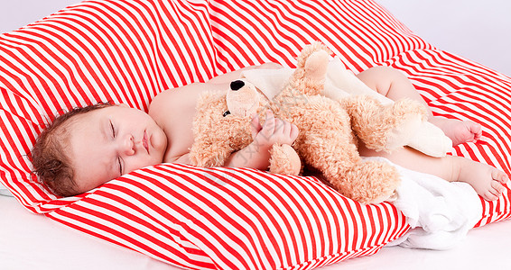 红色条纹枕头睡着的可爱小宝宝 在红色和白条纹枕头上眼睛婴儿生活女孩皮肤就寝女儿童年压痛男生背景