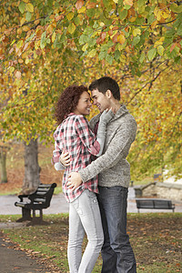秋季公园的罗姆青少年夫妇笑声拥抱两个人夫妻混血微笑树叶男性亲热女士背景图片