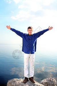 幸福快乐的青少年微笑天空岩石青年享受蓝色阳光衬衫男人乐趣好的高清图片素材