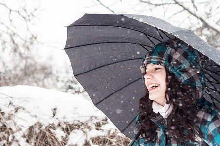 雪中带着雨伞的女孩乐趣雪花降雪女士幸福女性假期头发天气蓝色背景图片