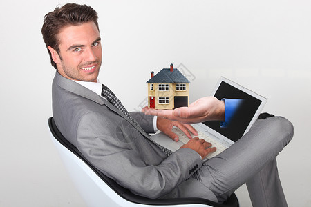 舒适椅子模型穿着灰色西装的青年男子坐在笔记本电脑上 手露出屏幕背景