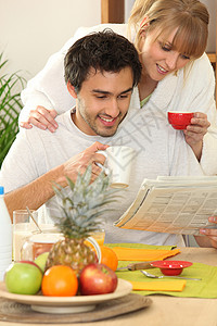 夫妻早餐看报纸一对夫妇在早餐时看报纸夫妻女朋友快乐阅读厨房水果玻璃幸福牛奶女士背景