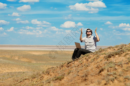 男人用笔记本电脑向上帝祈祷太阳沙漠商业天空旅行自由沙丘蓝色工作人士背景图片
