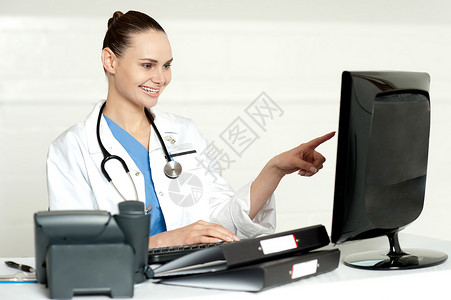 指向计算机屏幕的女医学专家;键盘高清图片素材