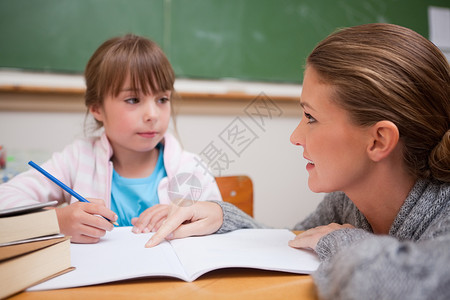 女学生在老师说话的时候写字年轻的高清图片素材