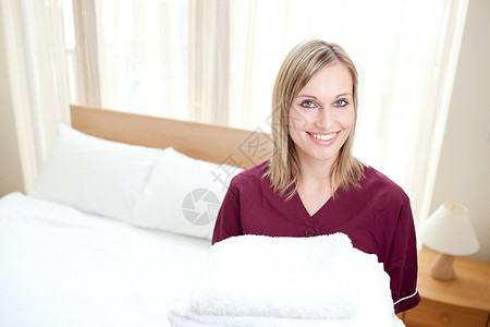 在旅馆房间里拿着毛巾的洗衣清洁女工(Radiant清洁女工)背景图片