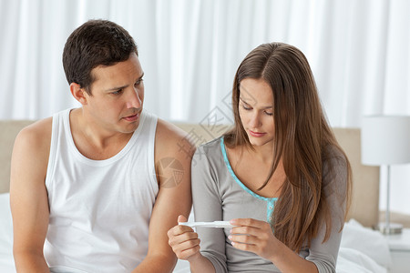 坐在床上看着怀孕测试的夫妻们都担心着呢高清图片