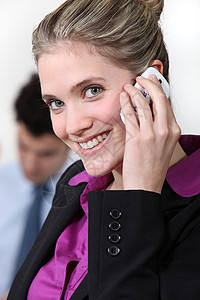 微笑的女商务人士用手机打她的手机背景图片