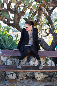 年轻女士坐在植物园的长椅上高清图片