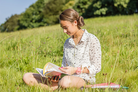 美丽的年轻学生在公园里读一本书青年大学快乐青少年校园女士学习教育女孩文件夹学术的高清图片素材