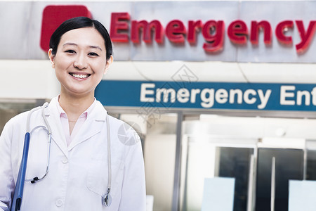 外出医院时微笑的女医生肖像 背景中有急救室标志AC 54970权威头发职业快乐急诊室棕色女性文字专业医护人员背景图片