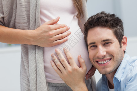 男人听他怀孕妻子肚子里的东西图片素材