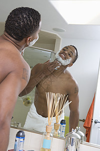 年轻人在浴室镜子前脸部涂剃须膏的年轻人背景图片